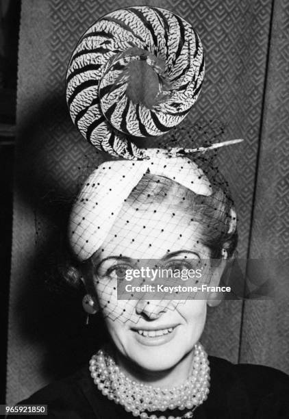 Présentation d'un bibi de sisal blanc orné de plumes de faisans et d'une voilette, création de Hugh Besford, à Londres, Royaume-Uni le 30 mars 1954.