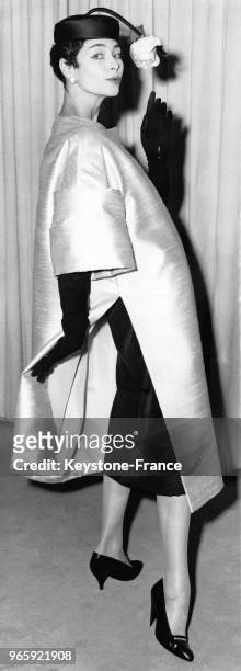 Mannequin portant le modèle 'Singapour' de Christian Dior de la Collection Printemps 1957: un manteau de pure soie de couleur crème avec des manches...
