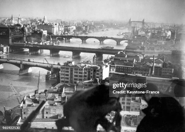Deux ouvriers travaillent en altitude sur la cheminée d'une usine en construction près de Southwark et de London Bridge le 17 janvier 1952 à Londres,...