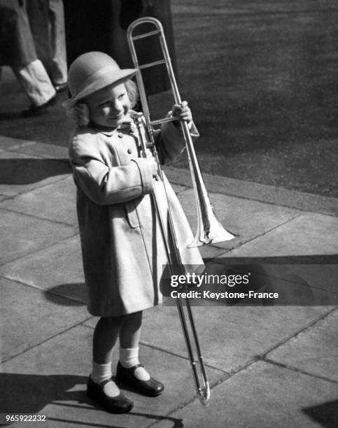 Une petite fille de quatre ans porte le trombone de son père, qui participe au National Brass Band Championship le 13 avril 1957 à Londres,...