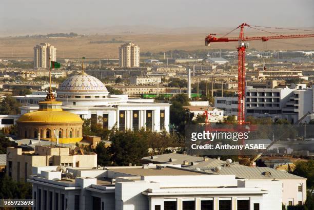 City with buildings, domed structure of parliament building with flag, Ashgabat,Turkmenistan.