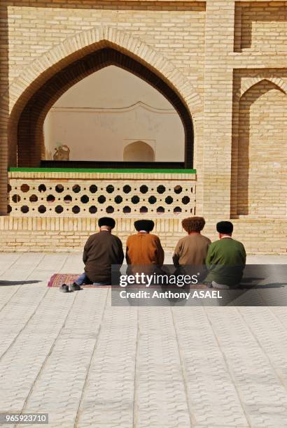 Four men praying in courtyard outside ancient mosque, Merv, Turkmenistan.