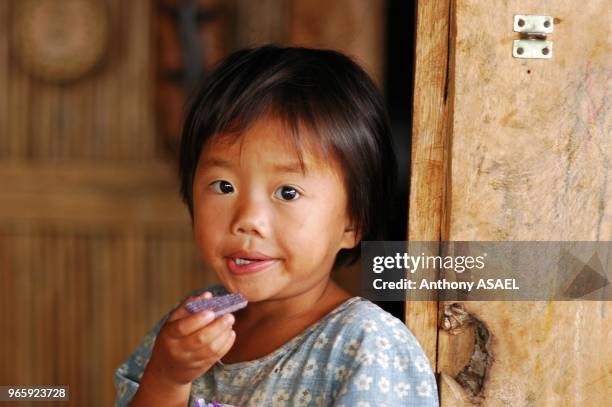 Philippines, Banaue, an Asian girl against wooden wall holding a biscuit packet.