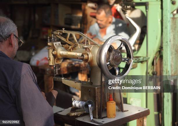 Cordonnier traditionnel utilsant une machine Singer au Souk de Koweit. Les artisans travaillent encore a la main pour confectionner ou reparer des...
