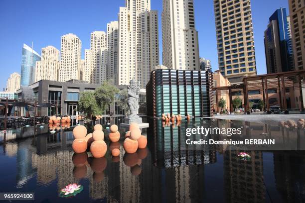 The Walk" est une avenue commerçante de Dubai Marina. Bassin thailandais sur une place de la rue. Statue thai et scupltures modernes au pied des...