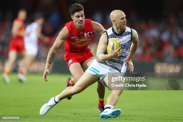 Gary Ablett of the Cats runs the ball from Alex Sexton of the Suns during the round 11 AFL match between the Gold Coast Suns and the Geelong Cats at...