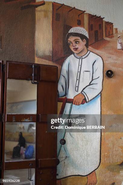 Peinture murale sur un mur du souk de Koweit. Scene de rue dans un village koweitien, enfants jouant dans la rue. Sur le miroir se reflete une femme....