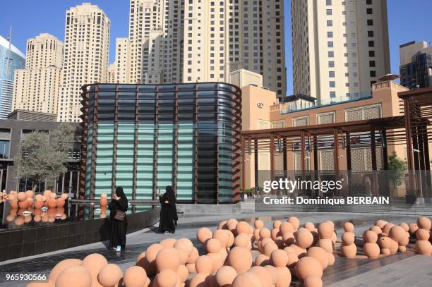 The Walk" est une avenue commerçante de Dubai Marina. Bassin thailandais sur une place de la rue. Statue thai et scupltures modernes au pied des...