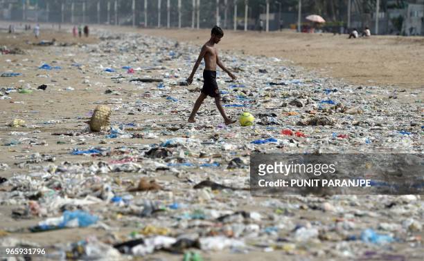 An Indian boy walks through plastic waste on Juhu beach in Mumbai on June 2, 2018.