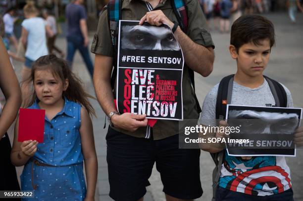 An Ukranian family holds red cards and banners during a protest demanding the release of the Ukrainian filmmaker and writer,Oleg Sentsov at the Main...