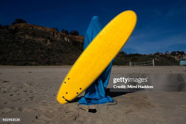 person covered in blue fabric holding yellow surfboard - surf life saving stockfoto's en -beelden