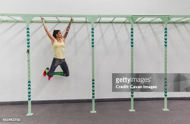 athlete hanging on monkey bars in gym - monkey bars imagens e fotografias de stock