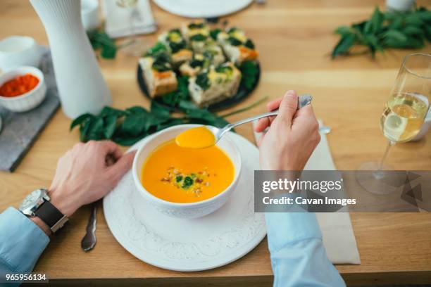 cropped image of man having pumpkin soup at dining table - spoon in hand stock pictures, royalty-free photos & images