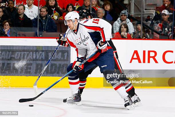 Eric Fehr of the Washington Capitals tries to carry the puck up ice while being closely checked by Peter Regin of the Ottawa Senators in a game at...