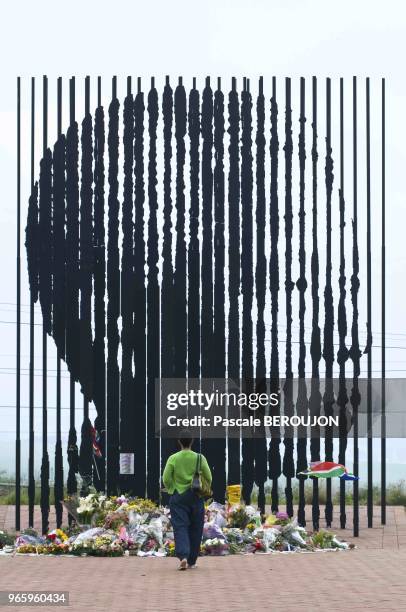 Une jeune femme au pied de la statue de Nelson Mandela le 13 decembre 2013 a Howick, Kwazulu Natal, Afrique du Sud. Des fleurs et messages sont...