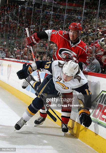 Joni Pitkanen of the Carolina Hurricanes collides along the boards with Tim Kennedy of the Buffalo Sabres during a NHL game on February 11, 2010 at...