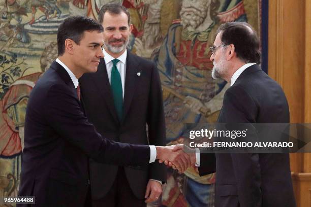 Spain's new Prime Minister Pedro Sanchez shakes hands with outgoing premier Mariano Rajoy next to Spain's King Felipe VI during a swearing-in...