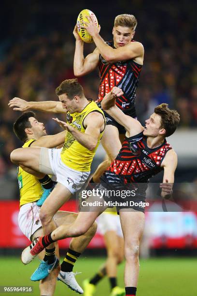 Matt Guelfi of the Bombers takes a high mark over Trent Cotchin of the Tigers and Kane Lambert during the round 11 AFL match between the Essendon...