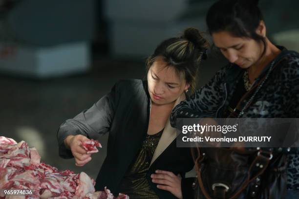 Jeunes femmes en train de choisir la viande à un étal de boucher, Bazar Chorsu à Tachkent, Ouzbekistan.