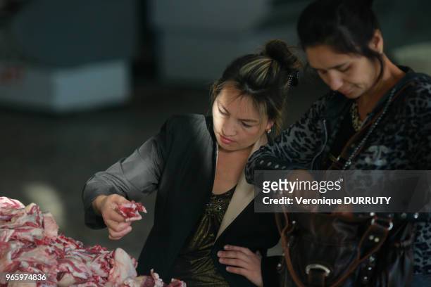 Jeunes femmes en train de choisir la viande à un étal de boucher, Bazar Chorsu à Tachkent, Ouzbekistan.