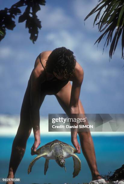 Femme tenant une tortue imbriquée dans les îles Aldabra aux Seychelles, le 20 novembre 1982.