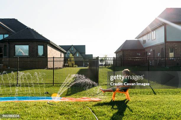 boy in swimming goggles sitting on chair at backyard against clear sky - fences 2016 film stock-fotos und bilder