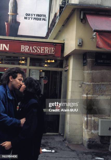 Jeune couple dans la rue devant une affiche de prévention pour le port du préservatif, à Paris, le 24 février 1989, France.