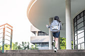 Back to school education concept with kid (elementary student girl) carrying backpacks going, running to class on school first day and walking up building stair happily