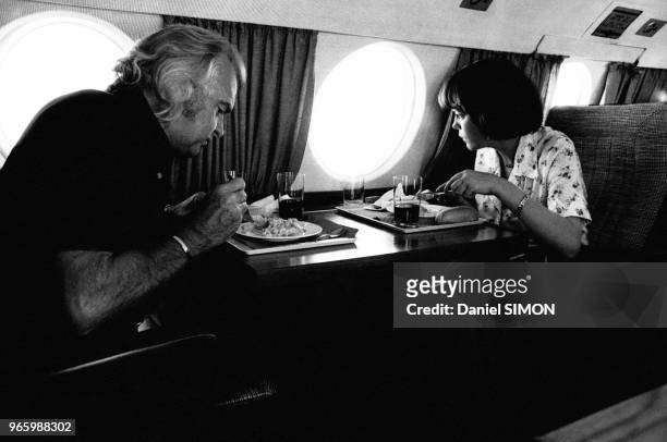 Imprésarion Johnny Stark et la chanteuse Mireille Mathieu, regardant par le hublot, devant un plateau repas dans l'avion pour Nice afin d'assister au...