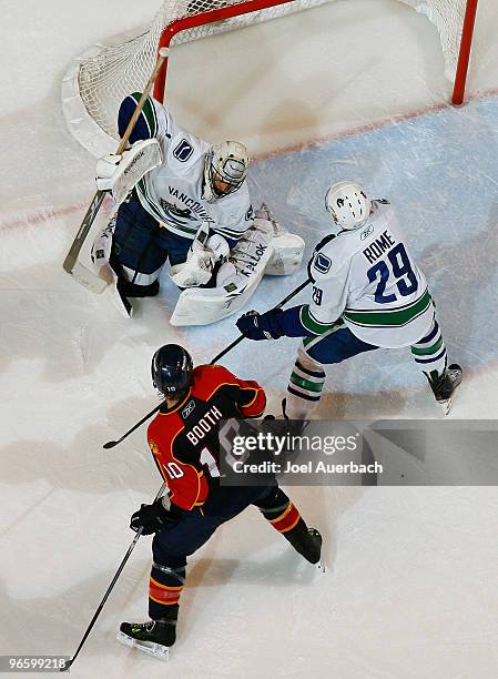 Aaron Rome helps defend the net as goaltender Roberto Luongo of the Vancouver Canucks stops a shot from David Booth of the Florida Panthers on...