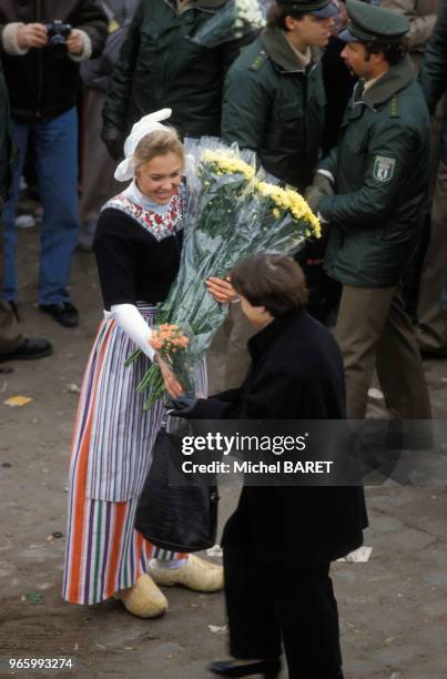 Jeune femme distribuant des fleurs lors d'un rassemblement après la chute du Mur de Berlin, le 14 novembre 1989, Allemagne.
