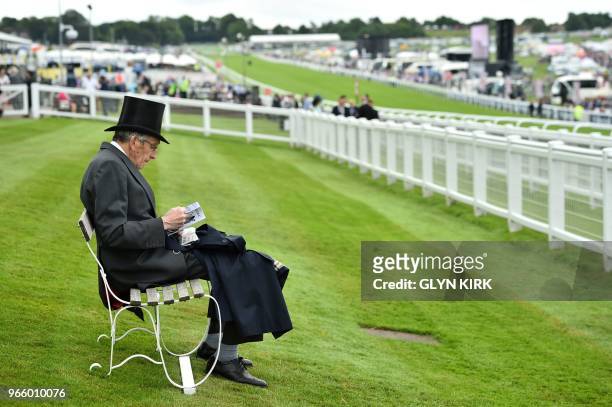 Racegoer reads his cards in the Queen's Stand on the second day of the Epsom Derby Festival in Surrey, southern England on June 2, 2018.