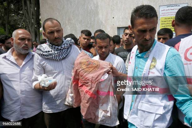 Father of 21 years old Razan al-Najjar holds her jacket covered with blood during her funeral after she was shot dead by Israeli soldiers, in Khan...