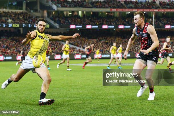 Shane Edwards of the Tigers kicks the ball past Brendon Goddard of the Bombers during the round 11 AFL match between the Essendon Bombers and the...