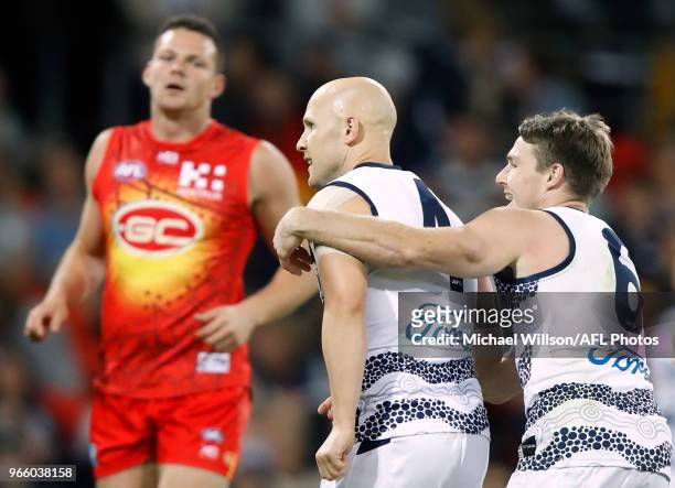 Gary Ablett and Lincoln McCarthy of the Cats celebrates as Steven May of the Suns looks on during the 2018 AFL round 11 match between the Gold Coast...