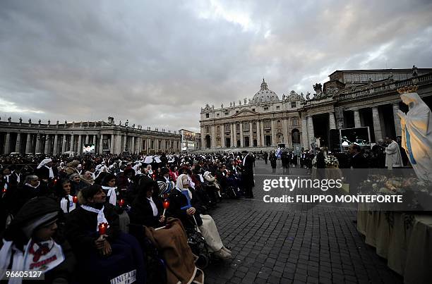 Faithful pray in front of a statue of Our Lady of Lourdes during a candle light celebration in St Peter's Square on the occasion of the Feast of Our...