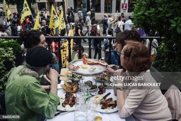 People eat at the terrasse of a restaurant while protesters walk past during a demonstration calling for the legalisation of undocumented immigrants...