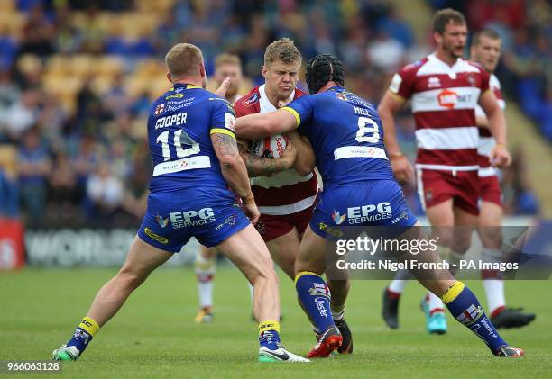 Warrington Wolves Mike Cooper and Chris Hill tackle Wigan Warriors Ryan Sutton during the Ladbrokes Challenge Cup, quarter final match at the...