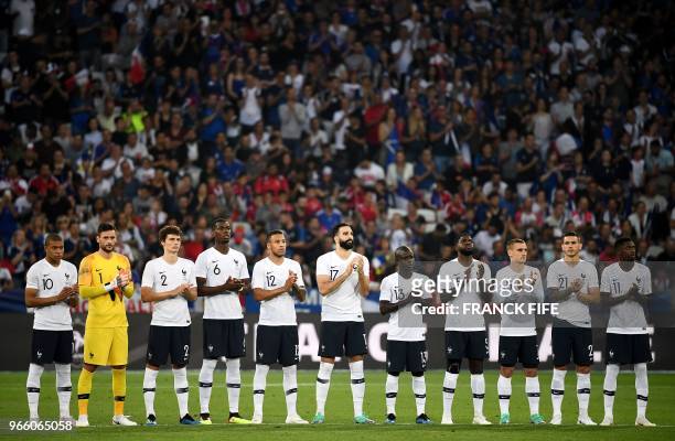 France's players applaud standing in lines during a homage to late French football player Roger Piantoni who died on May 26, before the friendly...