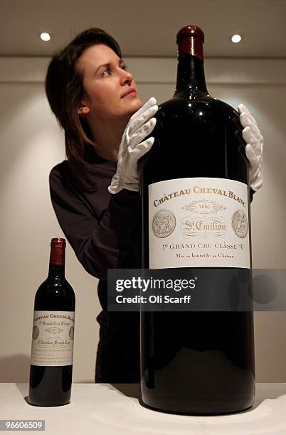 Gallery assistant for Sotheby's auction house admires a melchior of Chateau Cheval Blanc 2006 alongside a standard sized bottle on February 12, 2010...