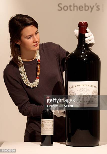 Gallery assistant for Sotheby's auction house admires a melchior of Chateau Cheval Blanc 2006 alongside a standard sized bottle on February 12, 2010...