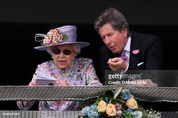 Britain's Queen Elizabeth II and the Queen's racing manager, John Warren attend the second day of the Epsom Derby Festival in Surrey, southern...