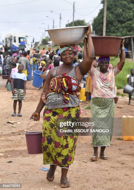 Women carry buckets of water after a worker of the National Office of Drinking Water distributed water to the population on June 2, 2018 in a...