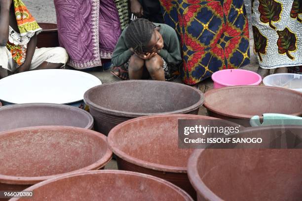 Child waits as workers of the National Office of Drinking Water distribute water to the population on June 2, 2018 in a district of Bouake, central...