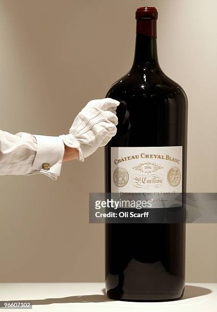 Gallery assistant for Sotheby's auction house cleans a melchior of Chateau Cheval Blanc 2006 on February 12, 2010 in London, England. The melchior...