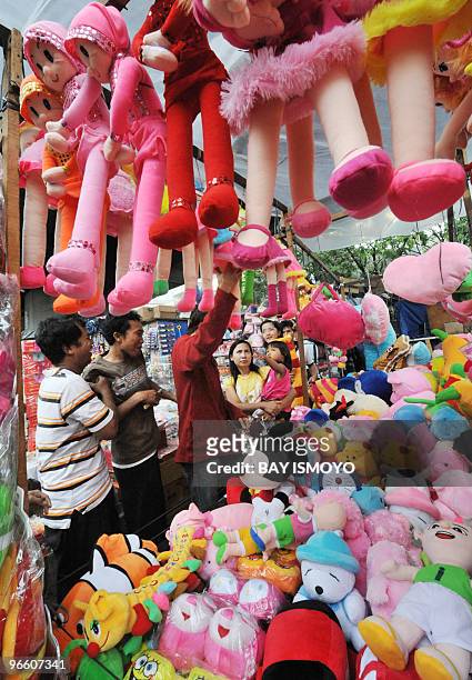 Young girl points her finger at Indonesian-made colourful dolls on display at a street stall in Jakarta on February 1, 2010. Statistics agency...
