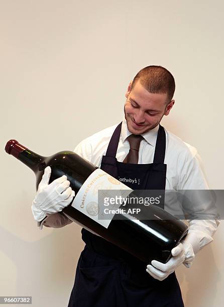 Sotheby's auction house employee poses for pictures with an 18 litre Melchior wine bottle during a photocall at the auction house in London, on...