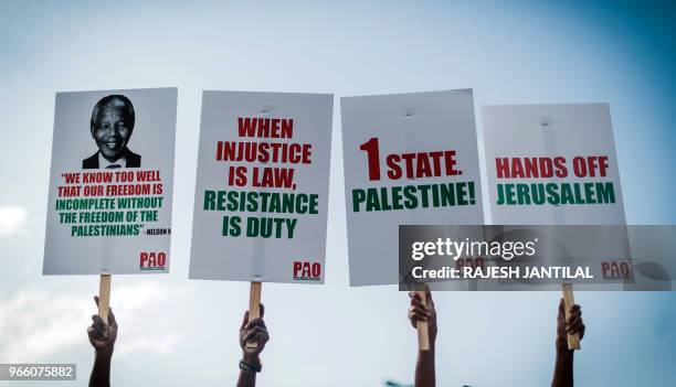 People hold placards during a demonstration by pro-Palestinian groups and other civil society organisations, in Durban on June 2, 2018 to protest...