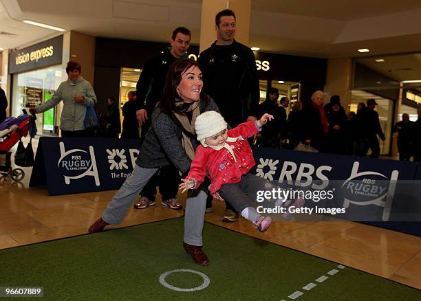 Martha Harrington aided by her Mother Sarah takes part watched by Wales players Matthew Rees and Ian Gough during the RBS Rugby challenge at St...