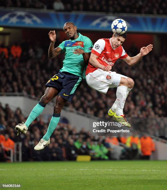 Robin van Persie of Arsenal and Eric Abidal of Barcelona both go for a high ball during the UEFA Champions League round of 16 first leg match between...